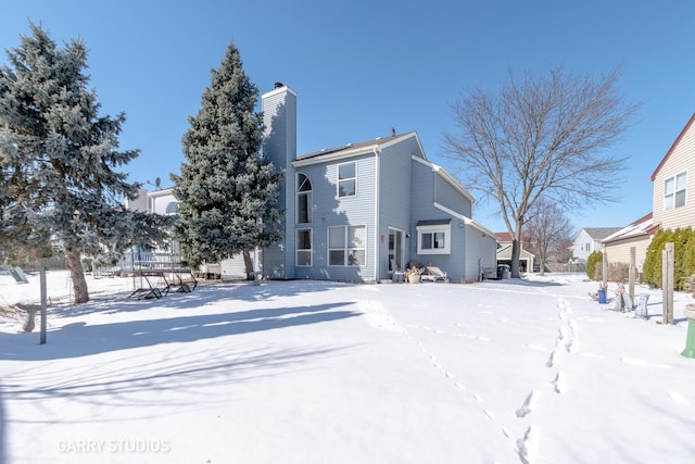 snow covered back of property featuring a chimney