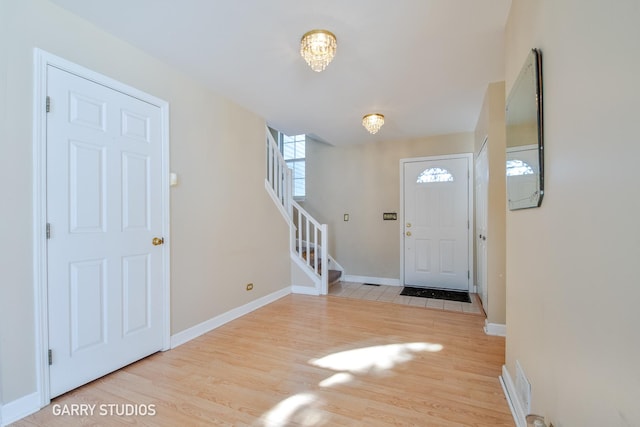 entrance foyer featuring light wood finished floors, stairway, and baseboards