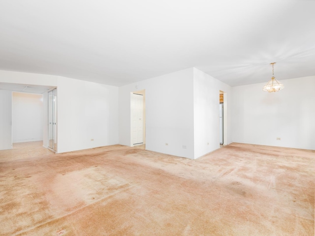 spare room with carpet floors and a chandelier