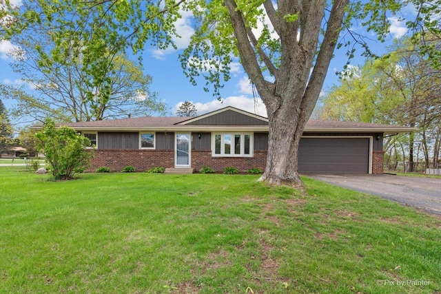 single story home with a garage, driveway, a front lawn, and brick siding