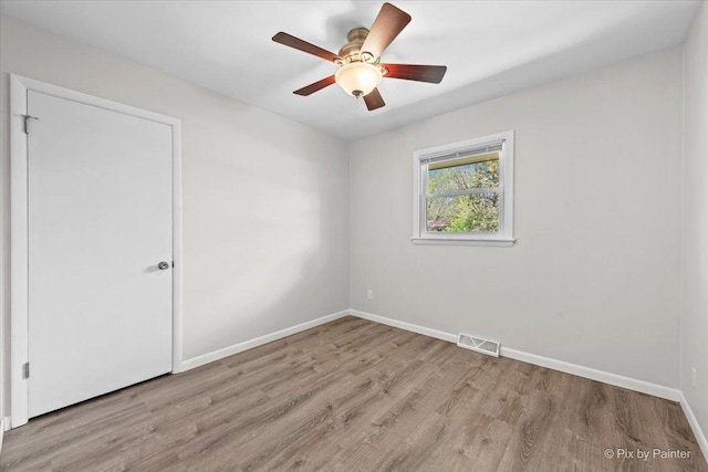 spare room featuring ceiling fan, baseboards, visible vents, and wood finished floors