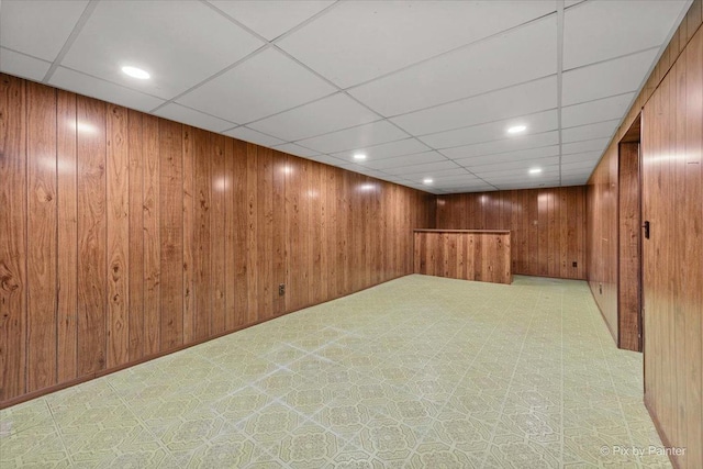 finished basement featuring recessed lighting, wood walls, and a paneled ceiling