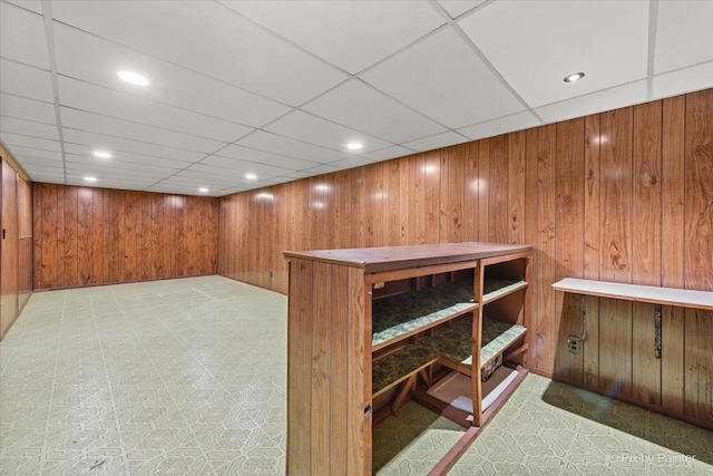 finished basement with recessed lighting, a drop ceiling, and wooden walls