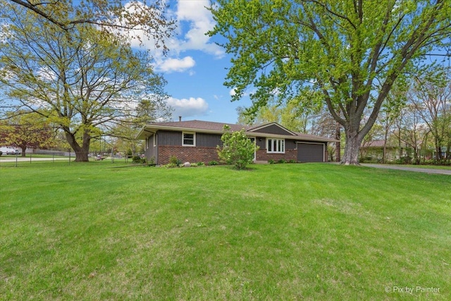 view of front facade with an attached garage, fence, a front yard, and brick siding