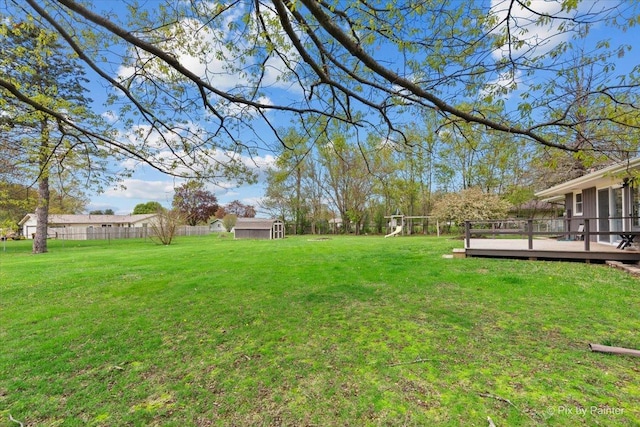 view of yard featuring a storage shed, a deck, an outdoor structure, and a fenced backyard