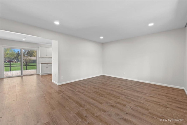 empty room featuring baseboards, recessed lighting, and wood finished floors