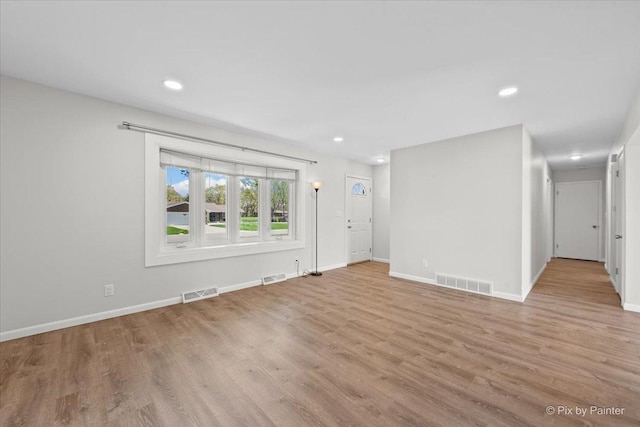 unfurnished living room with visible vents, baseboards, and wood finished floors