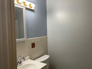 bathroom with vanity, toilet, and tile walls