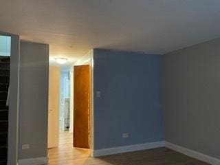 empty room featuring stairway, baseboards, and wood finished floors