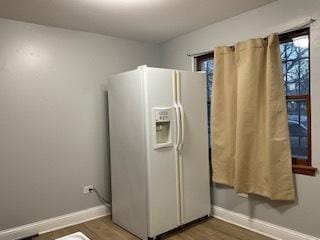 kitchen with white fridge with ice dispenser, baseboards, and dark wood finished floors