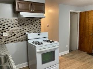 kitchen with light countertops, light wood-style flooring, dark brown cabinetry, white range with gas stovetop, and under cabinet range hood