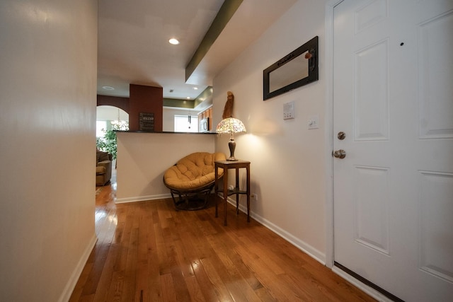 corridor featuring arched walkways, recessed lighting, baseboards, and hardwood / wood-style floors