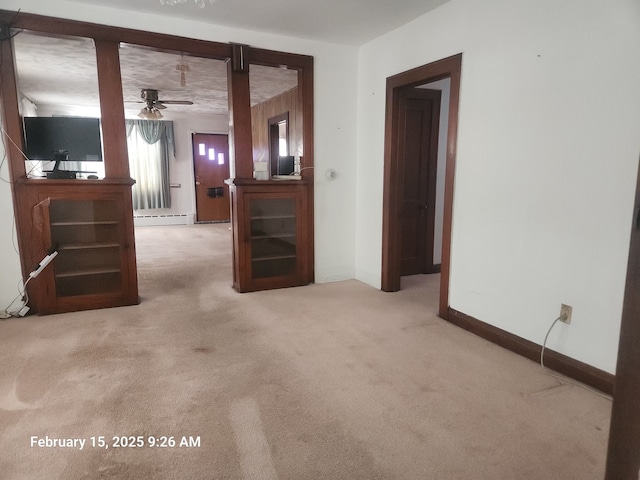 empty room featuring a ceiling fan, baseboards, carpet flooring, and baseboard heating