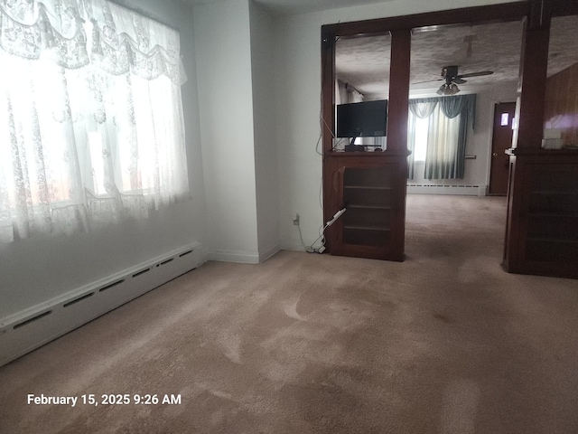 carpeted empty room featuring a baseboard heating unit and a ceiling fan