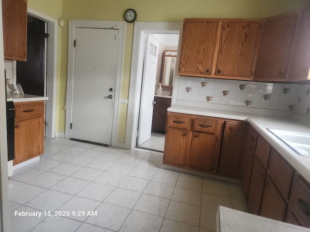 kitchen featuring brown cabinets, light tile patterned floors, light countertops, decorative backsplash, and a sink