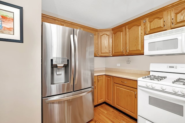 kitchen with brown cabinets, white appliances, light countertops, and light wood finished floors