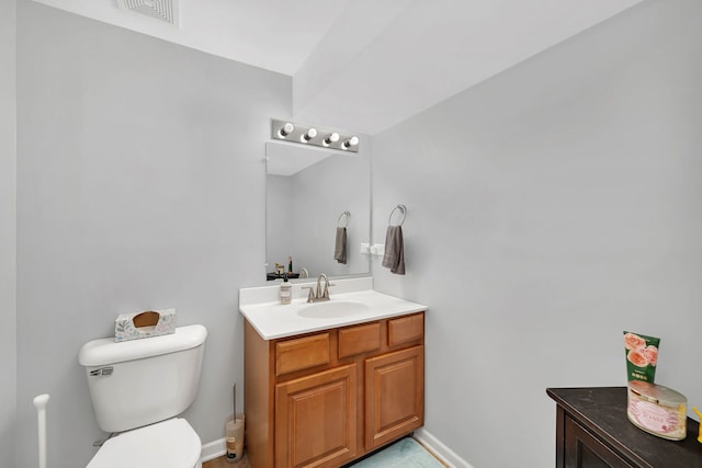 half bath with toilet, baseboards, visible vents, and vanity