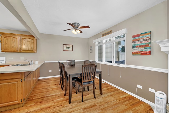 dining area with light wood-type flooring, baseboards, and a ceiling fan