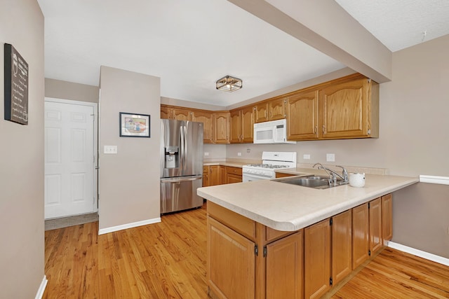 kitchen featuring brown cabinets, white appliances, light countertops, and a sink