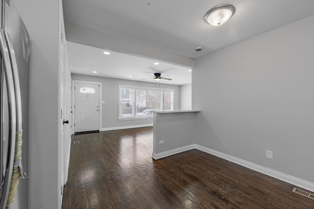empty room featuring visible vents, baseboards, ceiling fan, and dark wood-style floors