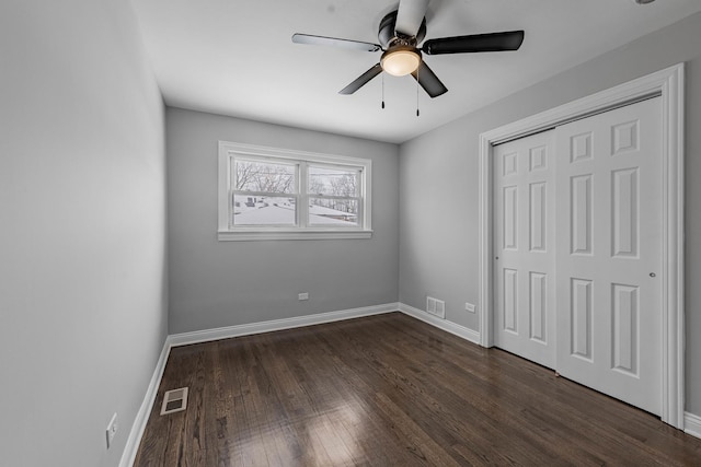 unfurnished bedroom featuring baseboards, ceiling fan, dark wood-style floors, and a closet