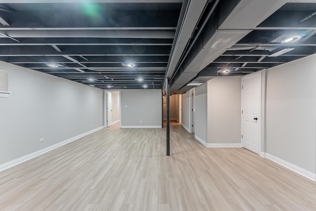 basement with baseboards, wood finished floors, and stairway