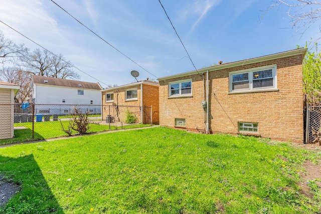 back of property with fence, a yard, and brick siding