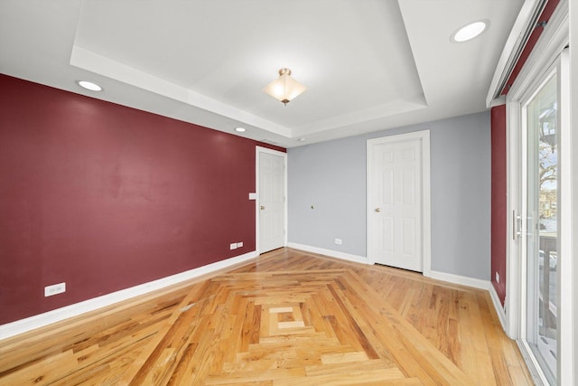 empty room featuring baseboards, a tray ceiling, and recessed lighting