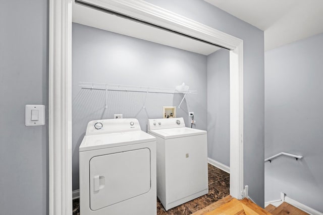 clothes washing area featuring laundry area, separate washer and dryer, dark wood finished floors, and baseboards