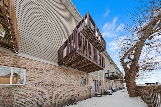 view of snow covered exterior with central AC and brick siding