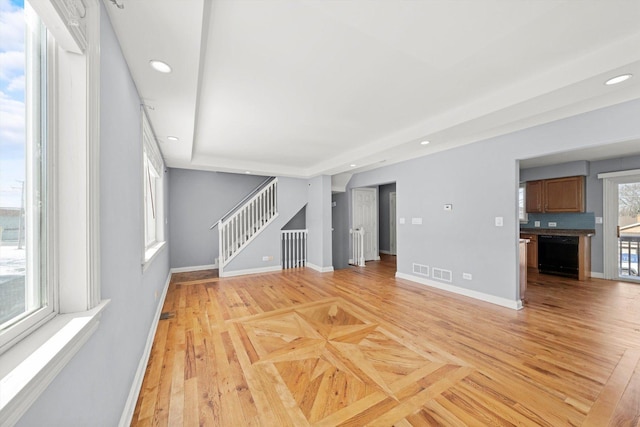 unfurnished living room featuring parquet flooring, baseboards, stairway, and recessed lighting