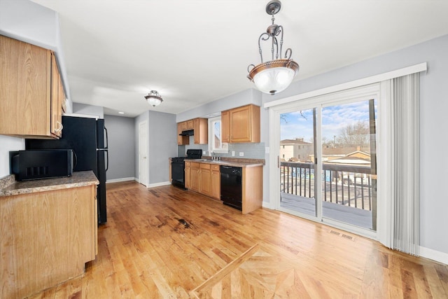 kitchen featuring visible vents, baseboards, hanging light fixtures, light countertops, and black appliances