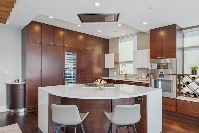 kitchen featuring a large island, modern cabinets, a breakfast bar, light countertops, and a sink