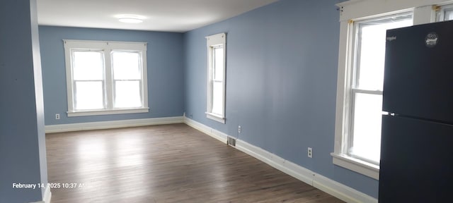 spare room featuring wood finished floors, visible vents, and baseboards