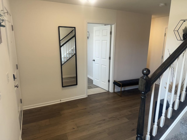 corridor with stairs, dark wood-style flooring, and baseboards