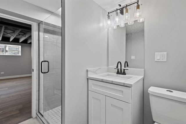 full bathroom with toilet, wood finished floors, vanity, baseboards, and a stall shower