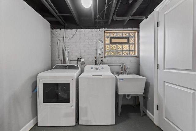 laundry area featuring a sink, laundry area, washing machine and dryer, and baseboards