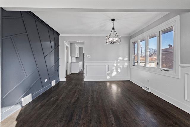 unfurnished dining area with dark wood-type flooring, visible vents, and a decorative wall