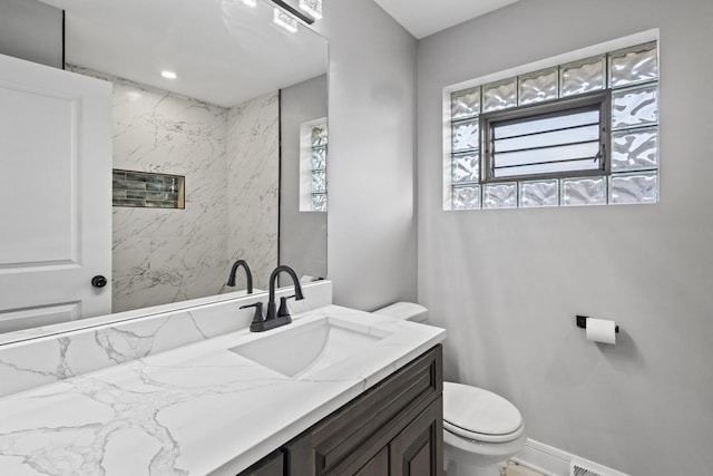 bathroom featuring baseboards, vanity, and toilet