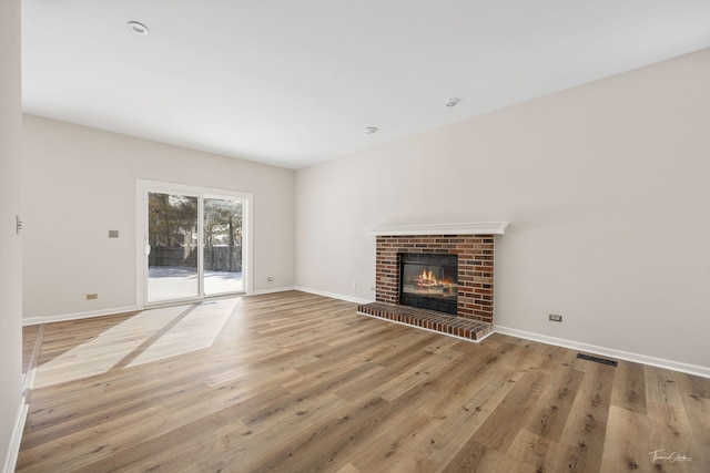 unfurnished living room featuring a brick fireplace, visible vents, light wood-style flooring, and baseboards