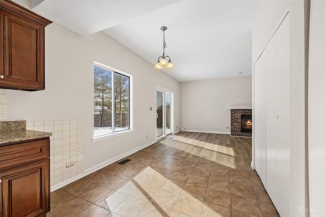 interior space featuring a fireplace, a notable chandelier, visible vents, tile patterned flooring, and baseboards