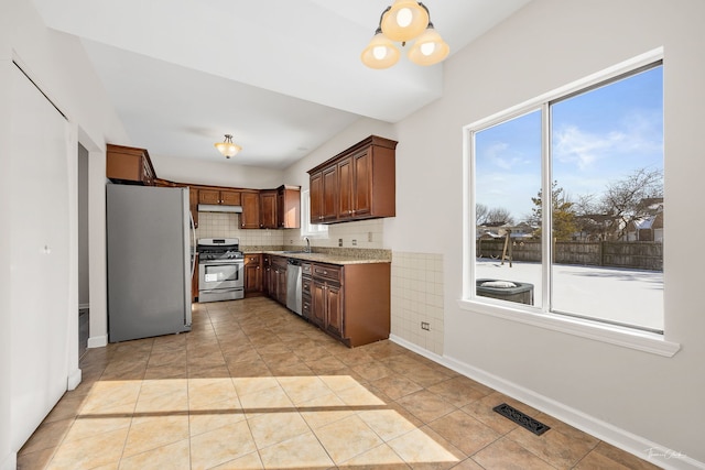 kitchen with visible vents, appliances with stainless steel finishes, a sink, under cabinet range hood, and backsplash