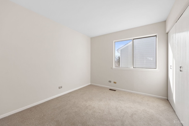 spare room with light carpet, visible vents, and baseboards