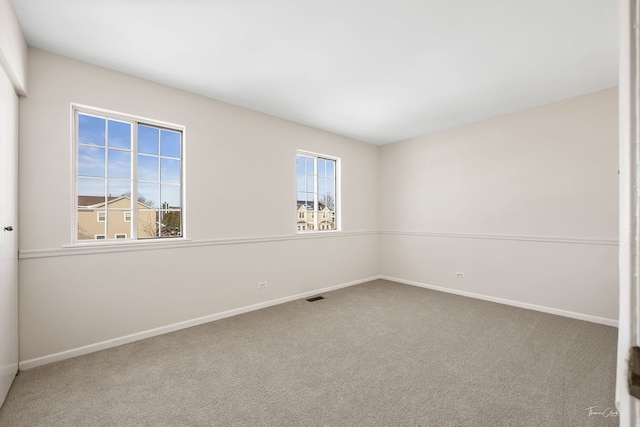 unfurnished room with carpet floors, visible vents, and baseboards