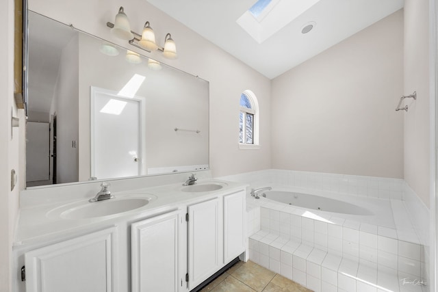 full bathroom with vaulted ceiling with skylight, double vanity, tile patterned flooring, and a sink