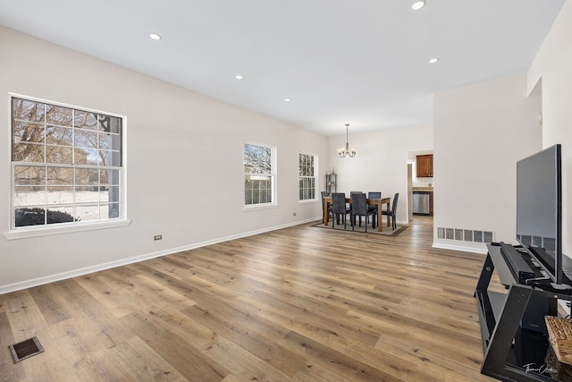 unfurnished living room with a chandelier, wood finished floors, visible vents, and recessed lighting