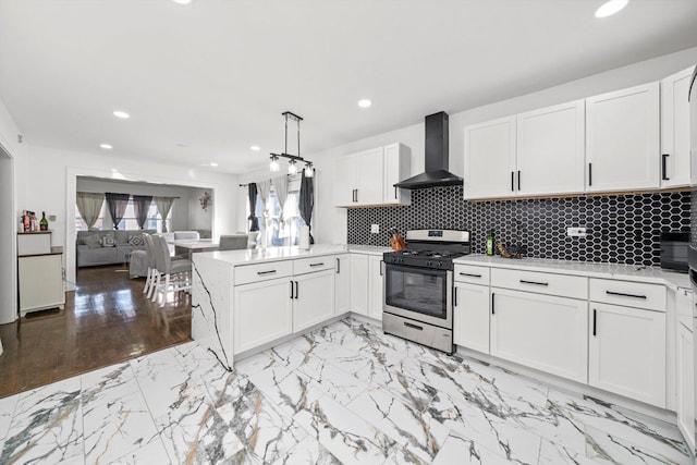 kitchen with white cabinets, wall chimney exhaust hood, a peninsula, light countertops, and stainless steel range with gas cooktop