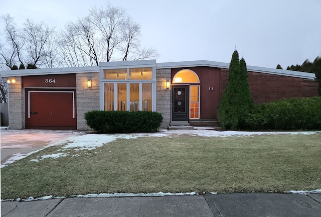 view of front facade featuring an attached garage, concrete driveway, stone siding, and a front yard