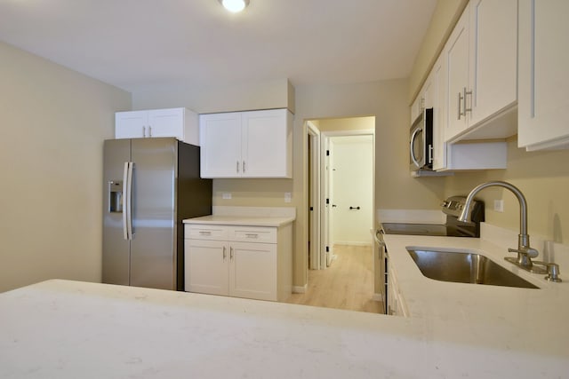 kitchen featuring white cabinets, a sink, stainless steel appliances, and light countertops