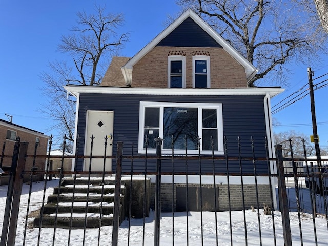 view of front facade featuring brick siding, fence, and roof with shingles